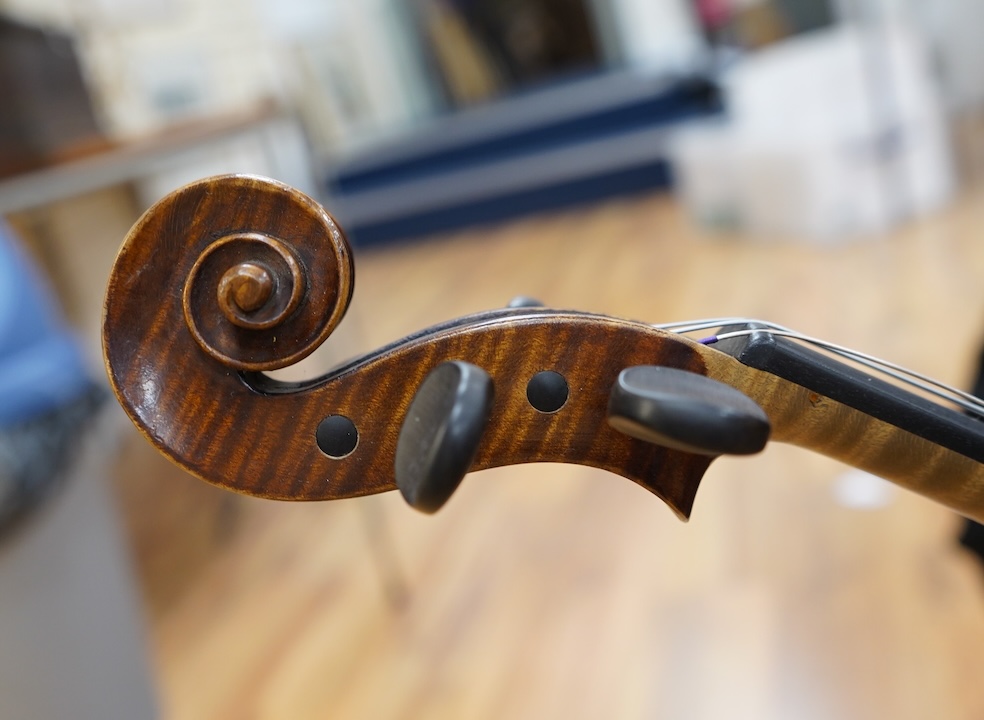 An early 20th century German violin, with a label reading ‘Copy of Joseph Guarnerius, Made in Germany’, body length 35.5cm, cased with a bow by Tourte. Condition - good.